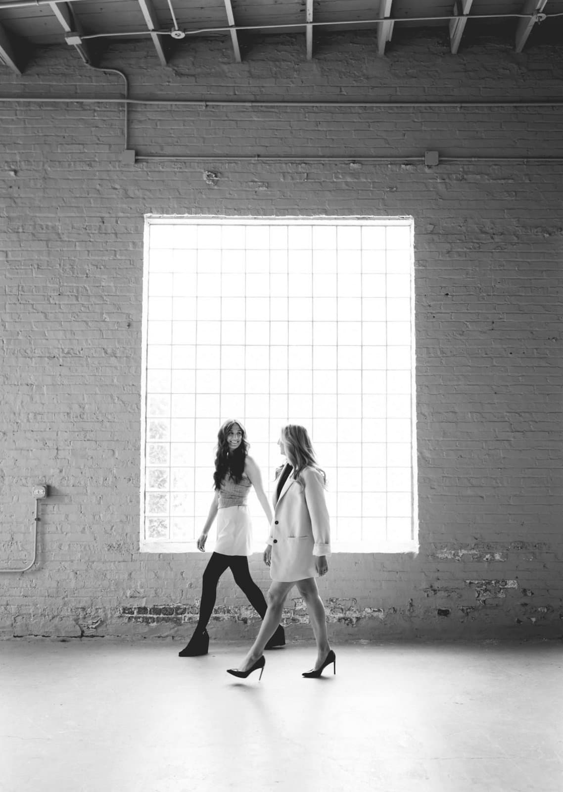Samantha and Michaela walking through a light-filled space